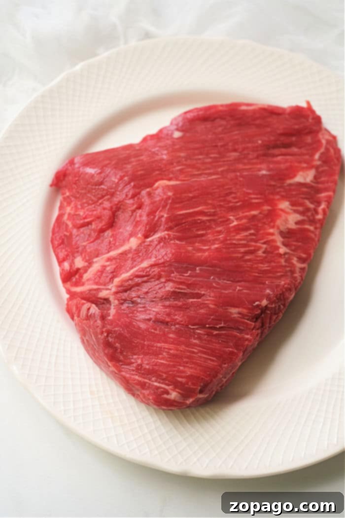 Savory Dry Rub Air Fryer Flank Steak 4 A raw flank steak rests invitingly on a white plate, just waiting to be transformed into a succulent dish in the air fryer.