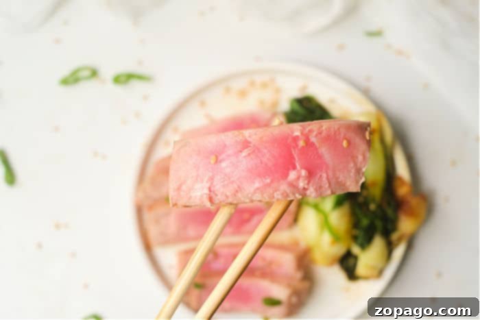 Air Fryer Tuna Steaks 7 Two seared tuna steaks served on a white plate with lemon wedges and fresh herbs.