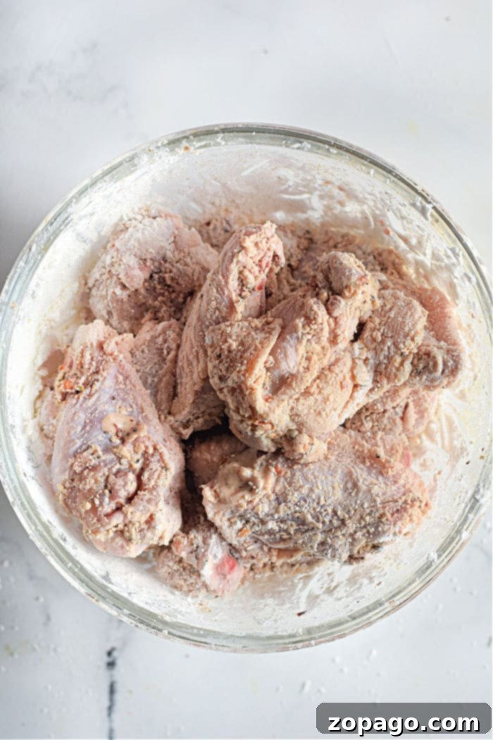 Dynamite Chicken 4 Raw firecracker chicken wings, coated in flour and seasoning, are perfectly prepped for their air fryer transformation.