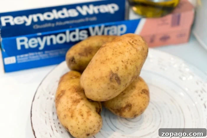 Easy Slow Cooker Baked Potatoes 3 Several slow cooker baked potatoes wrapped in foil, ready to be cooked to tender perfection.