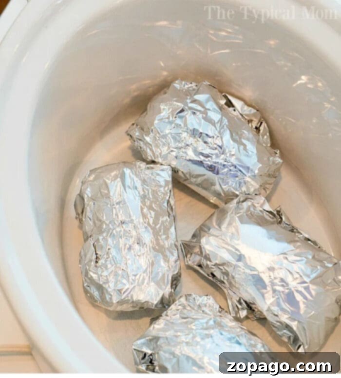Easy Slow Cooker Baked Potatoes 5 Close-up of slow cooker baked potatoes in foil, perfectly cooked and ready to be served.