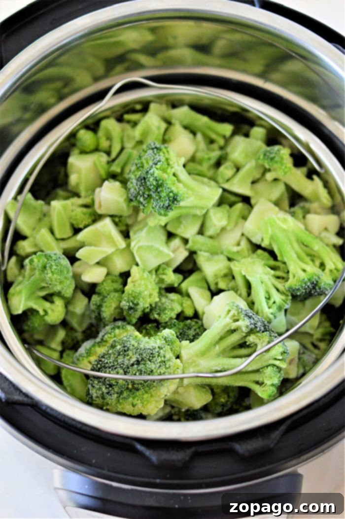 Instant Pot Frozen Broccoli 4 Frozen Broccoli florets steaming in an Instant Pot with a steamer basket