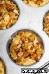 Spiced Sweet Potato Muffins 9 Close-up of muffin tin with unbaked sweet potato muffins topped with crumbly pecan streusel.