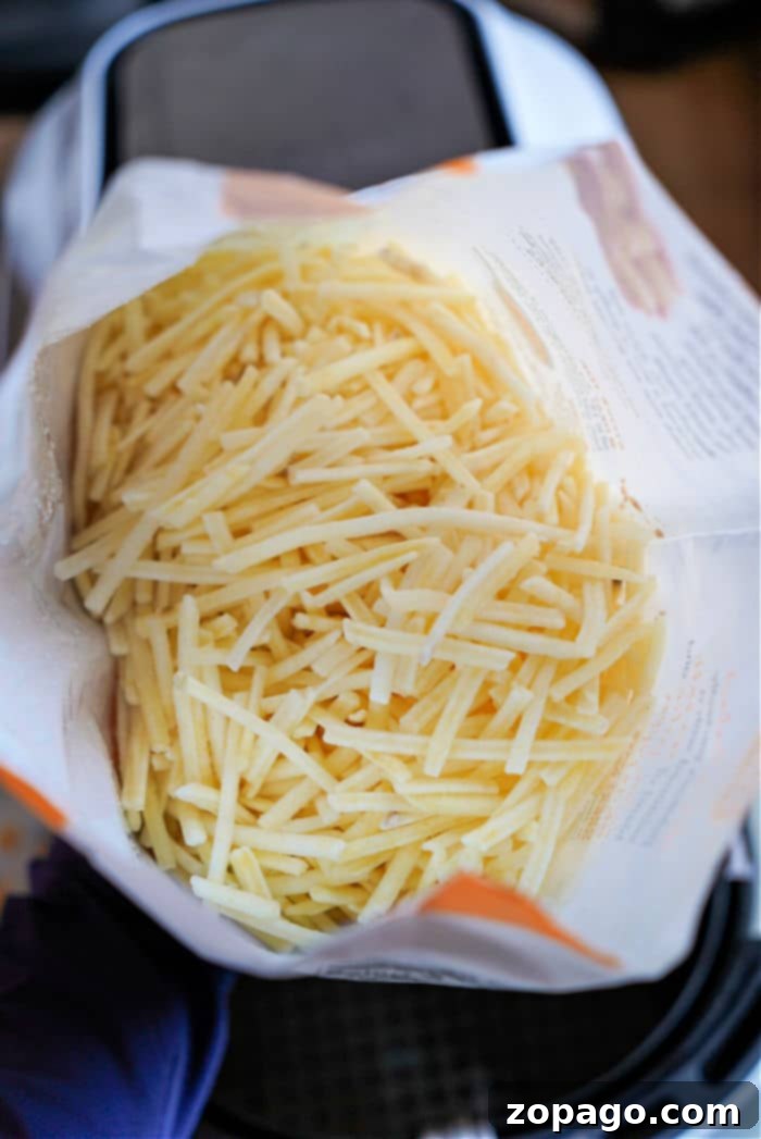 Perfectly Crispy Air Fryer Frozen Hash Browns 3 Crispy frozen hash browns cooking inside an air fryer basket, ready to be flipped and seasoned.