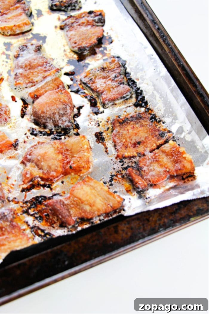 Succulent and Crispy Oven Pork Belly 6 Crispy pork pieces, reminiscent of how to cook pork belly in the oven, glisten on a foil-lined baking sheet.