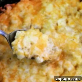 Slow Cooker Cheesy Hash Browns 9 A spoon scoops up a cheesy potato casserole, rich with creamy hashbrown potatoes, all topped with perfectly melted cheese.