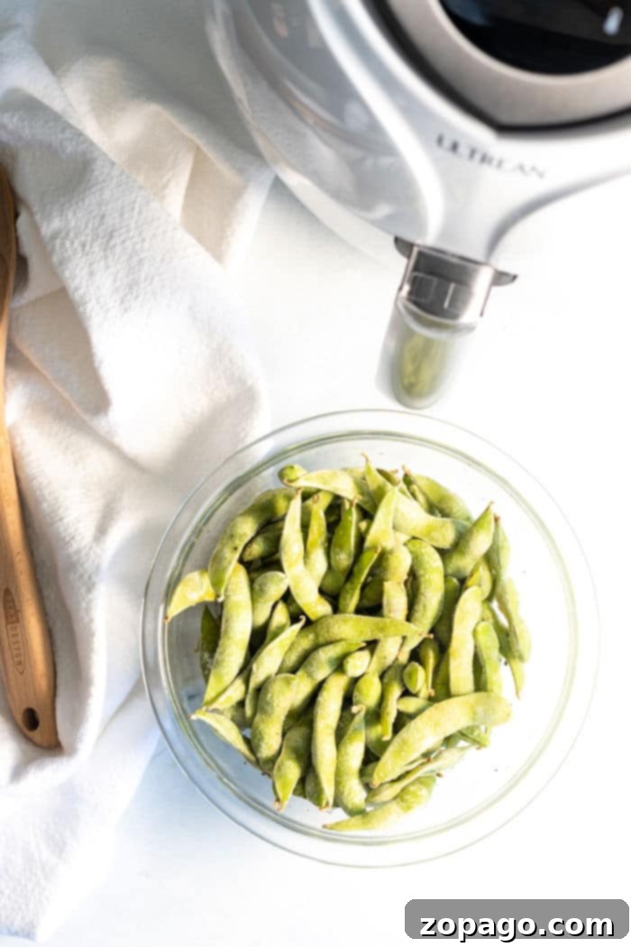Crispy Air Fryer Edamame Bites 3 A close-up shot of perfectly seasoned air fryer soy beans in their pods, arranged neatly in an air fryer basket.
