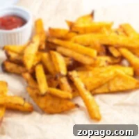 Crispy Turnip Fries 4 Golden baked turnip fries on parchment paper, crisped to perfection, with a small cup of ketchup in the background.