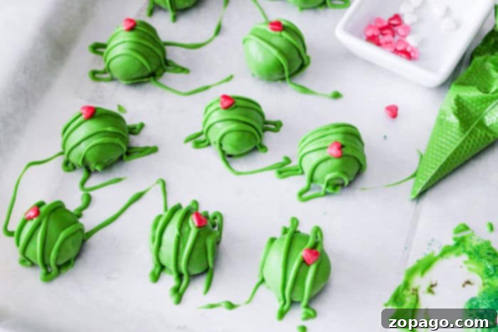 How the Grinch Stole Dessert 4 Festive green Christmas truffles adorned with red heart sprinkles, arranged on a white plate.
