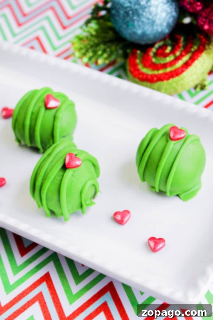 How the Grinch Stole Dessert 5 A festive display of green Grinch-themed Oreo balls with red heart sprinkles, perfect for holiday parties.