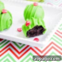 Green cake balls on a plate, one bitten, with heart sprinkles evoke a whimsical grinch dessert vibe against a zigzag pattern tablecloth.