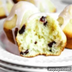 A healthy cranberry muffin with yogurt and glaze, cut in half, sits invitingly on a white plate.
