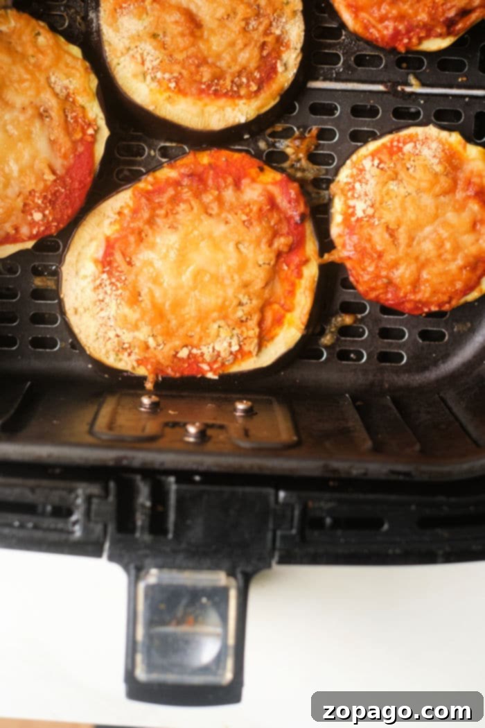 Low Carb Air Fryer Eggplant Parmesan 7 with cheese and tomato sauce cook to perfection in an air fryer basket, bringing a crisp texture similar to that of an air fryer eggplant parm.