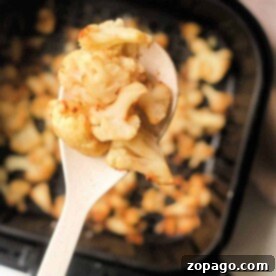 Perfectly Tender Air Fryer Frozen Cauliflower 8 Close-up of roasted cauliflower florets on a spoon, perfectly air-fried