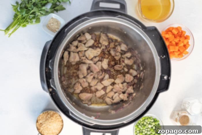 Bite-sized chicken pieces and diced onions being sautéed in the Instant Pot, forming the flavorful base for the chicken and rice dish.