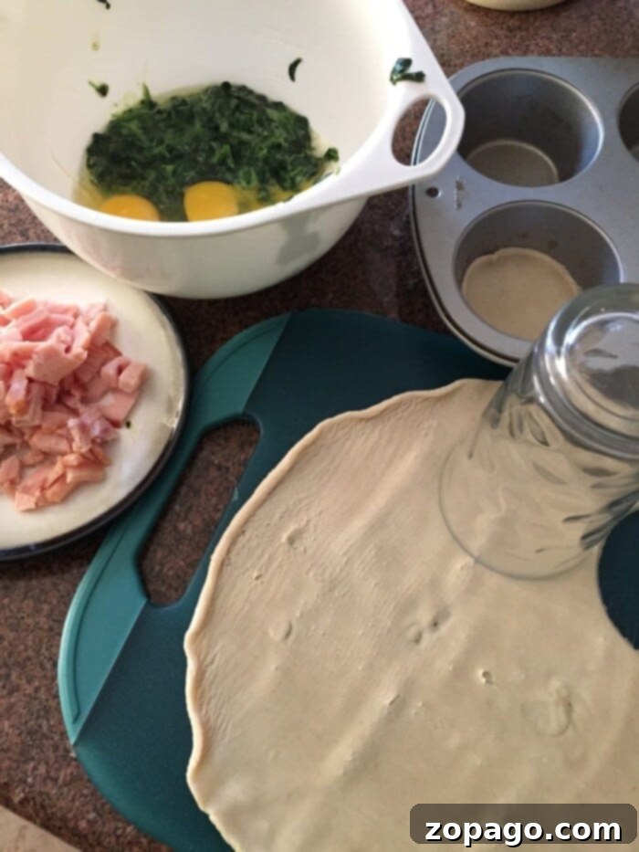 Ingredients for this easy mini quiche recipe: dough, bacon, eggs, and spinach mixed in a bowl, ready to fill a muffin tin on the counter.