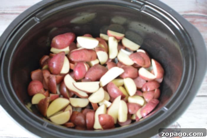 Hearty Slow Cooker Cabbage and Sausage 5 A hearty serving of Crockpot Cabbage, Sausage, and Potatoes in a white bowl, garnished with fresh parsley.
