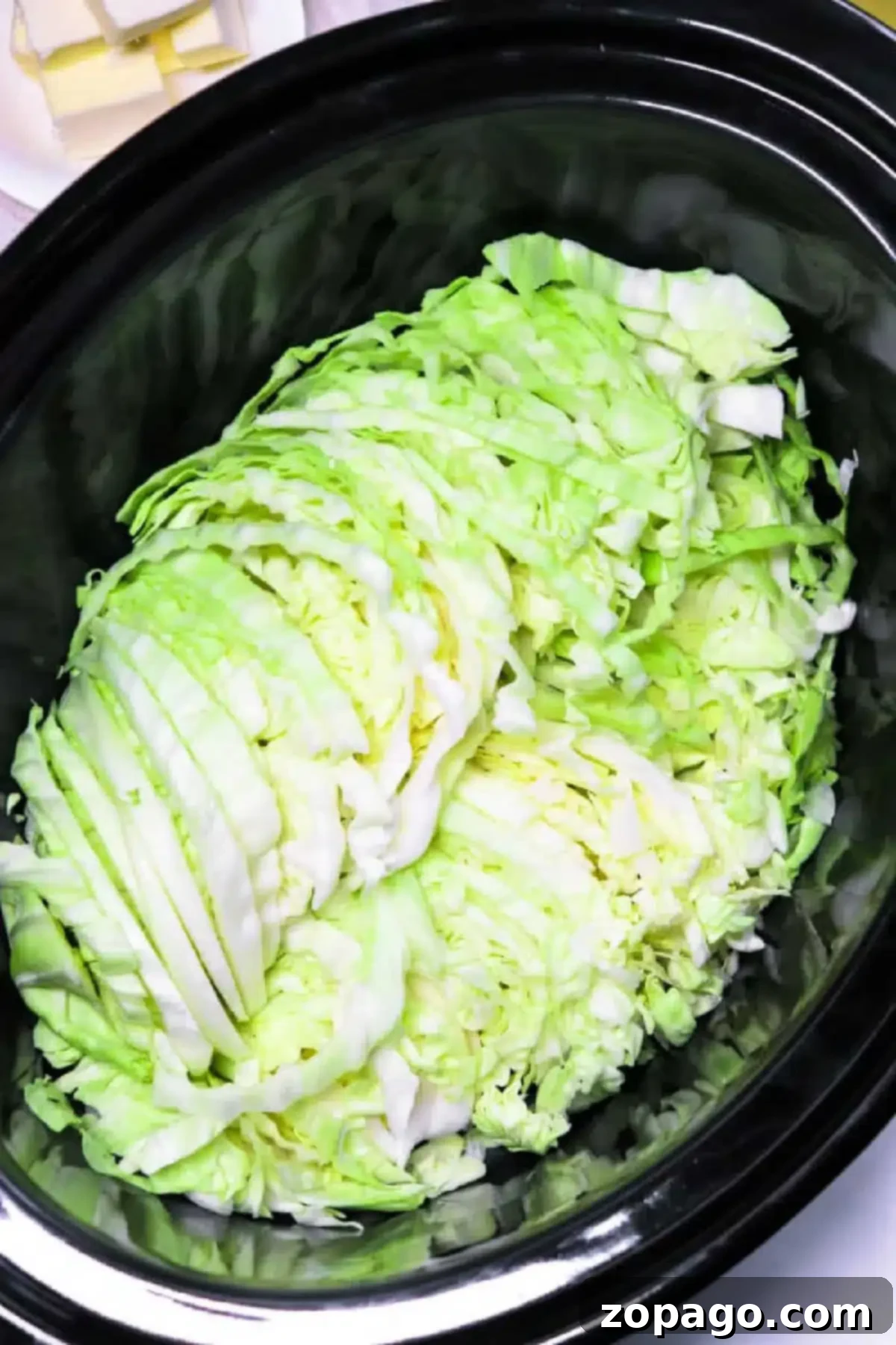 Easy Slow Cooker Cabbage 3 A heap of slow cooker cabbage rests inside a sleek black cooker, primed for a delicious transformation.
