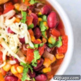 A hearty bowl of Instant Pot vegetarian chili with kidney beans, corn, diced tomatoes, shredded cheese, and fresh cilantro.