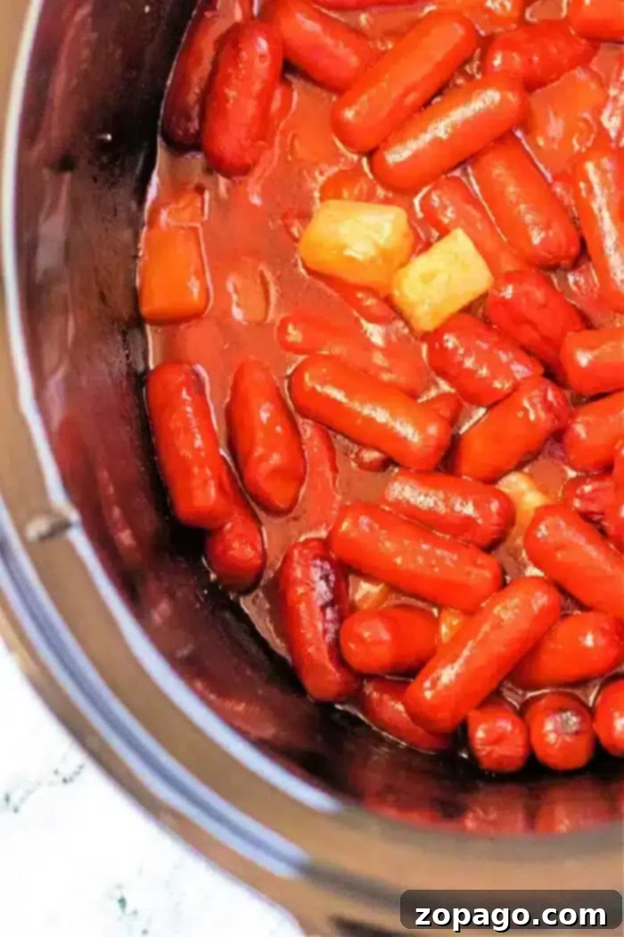 Sweet and Sticky Slow Cooker Sausages 2 A crockpot recipe featuring mini sausages in a savory sauce, perfectly mixed with chunks of pineapple.