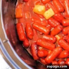 Discover the Crockpot Little Smokies recipe featuring pineapple chunks mingling in a savory sauce, all gently simmered to perfection inside your slow cooker.
