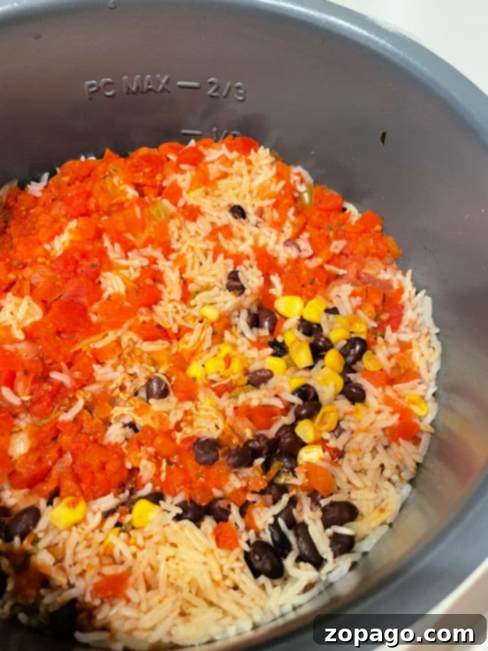 Instant Pot Leftover Chicken Makeovers 4 Rice, black beans, corn, and diced tomatoes are mixed together in an Instant Pot, with the option to add leftover chicken for extra flavor. The ingredients are partially cooked, showing distinct kernels of corn and tomato pieces. The cooker is marked with PC MAX – 2/3 on the side.