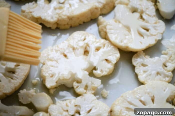 Perfectly Crisped Air Fryer Cauliflower Steaks 3 Baked cauliflower steaks on a sheet pan, seasoned and ready to eat