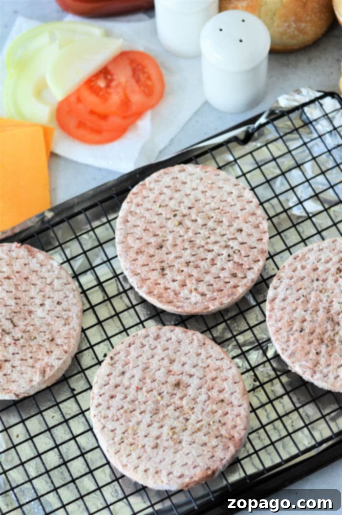 Frozen hamburger patties arranged on a wire rack for oven baking