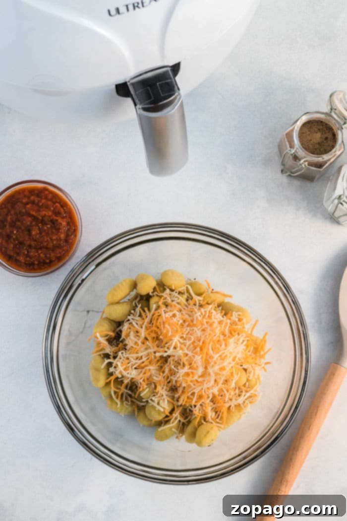 Crispy Ninja Foodi Air Fryer Gnocchi 4 Delicious pizza gnocchi in an air fryer basket, garnished with melted cheese and herbs.