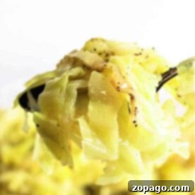 Close-up of cooked cabbage on a fork, seasoned with pepper, against a bright background, reminiscent of cozy crockpot cabbage recipes.