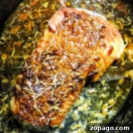 Pork roast topped with rosemary and onions, simmering in flavorful juices and Slow Cooker Pork Roast Onion Soup Mix for a savory, effortless meal.