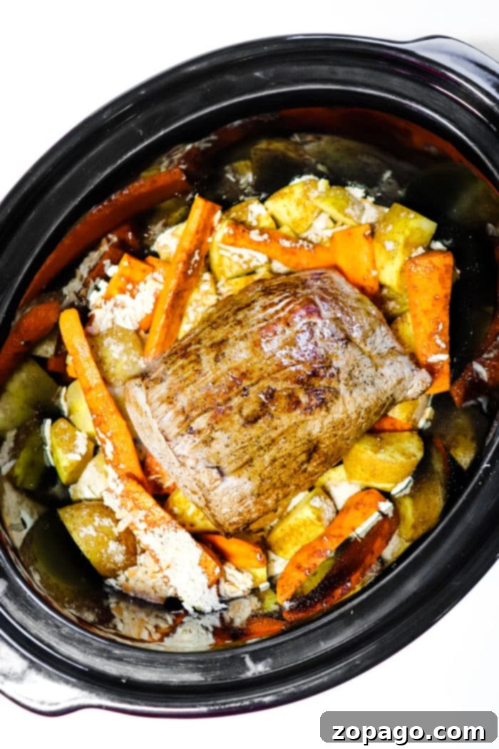 Effortless Slow Cooker Sirloin Roast 5 Large cut of Crockpot roast, simmering in rich gravy with vegetables, showcasing the slow cooking process