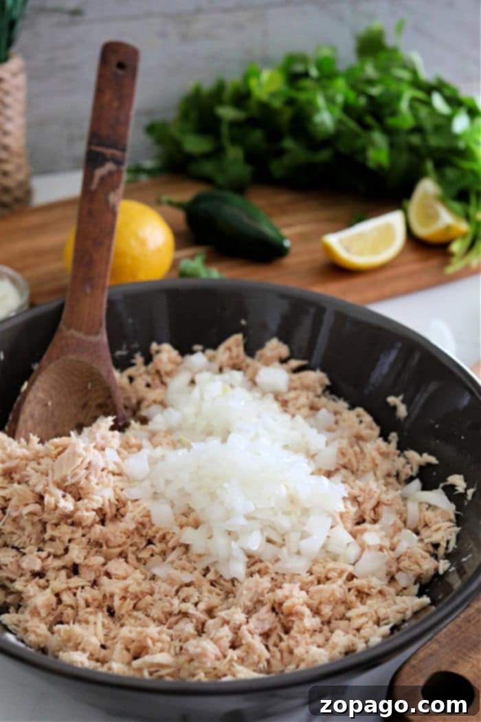 Crispy Air Fryer Tuna Patties 4 Fresh ingredients for tuna patties including chopped onions, shredded tuna, vibrant lemons, fresh cilantro, and a spicy jalapeño.