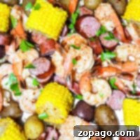 Easy Slow Cooker Shrimp Boil 7 A close-up of a delectable Crock Pot Shrimp Boil featuring plump shrimp, savory sausage, golden corn, and tender potatoes garnished with fresh parsley on a serving platter.