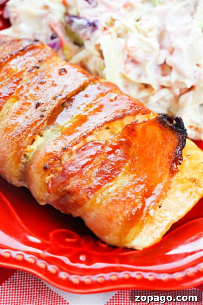 Crispy Bacon Wrapped Salmon 6 A slice of bacon-wrapped salmon served with a side of creamy coleslaw on a vibrant red plate, showcasing a delightful meal presentation.