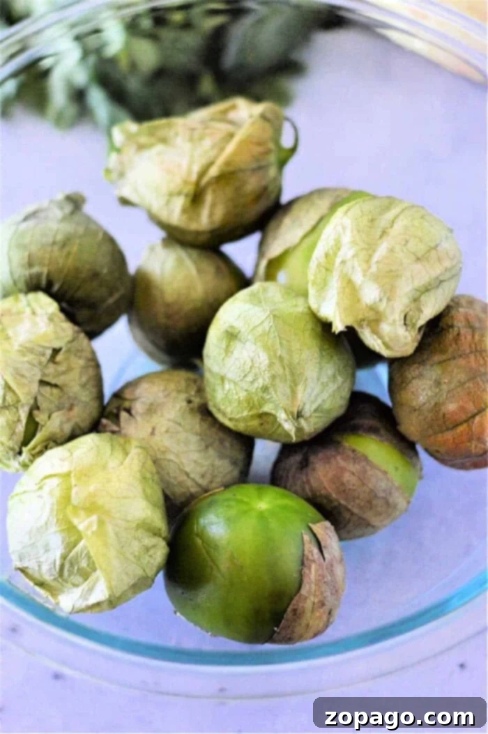 Unlocking the Flavor of Tomatillos 8 A selection of fresh tomatillos, some with husks, some without, displayed on a rustic wooden surface, emphasizing their readiness for cooking into various dishes.