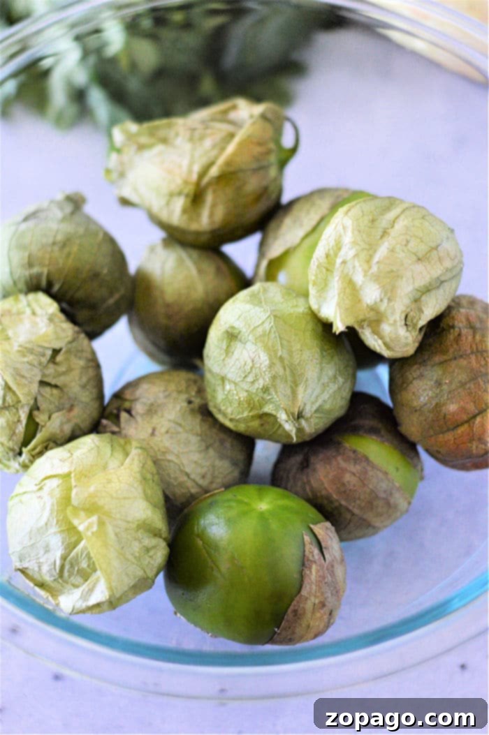 Unlocking the Flavor of Tomatillos 9 A top-down view of whole tomatillos with their husks partially removed, alongside some peeled ones, preparing for either roasting or boiling to make delicious salsa.