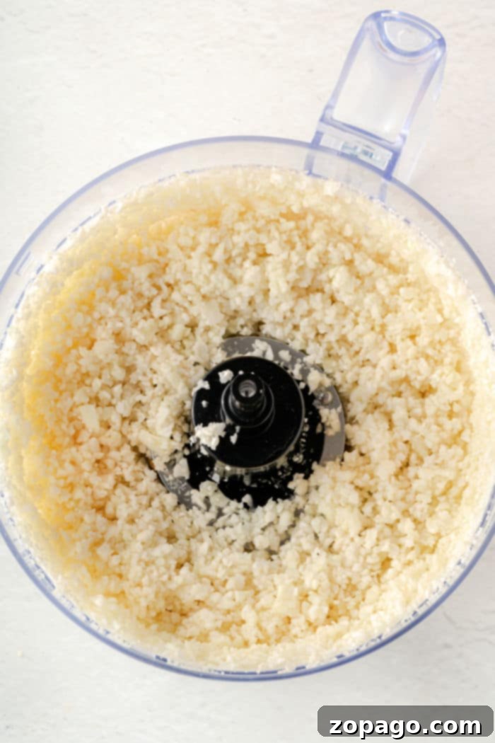 Savory Cauliflower Fritters 5 Cauliflower florets being processed into rice-like consistency in a food processor.