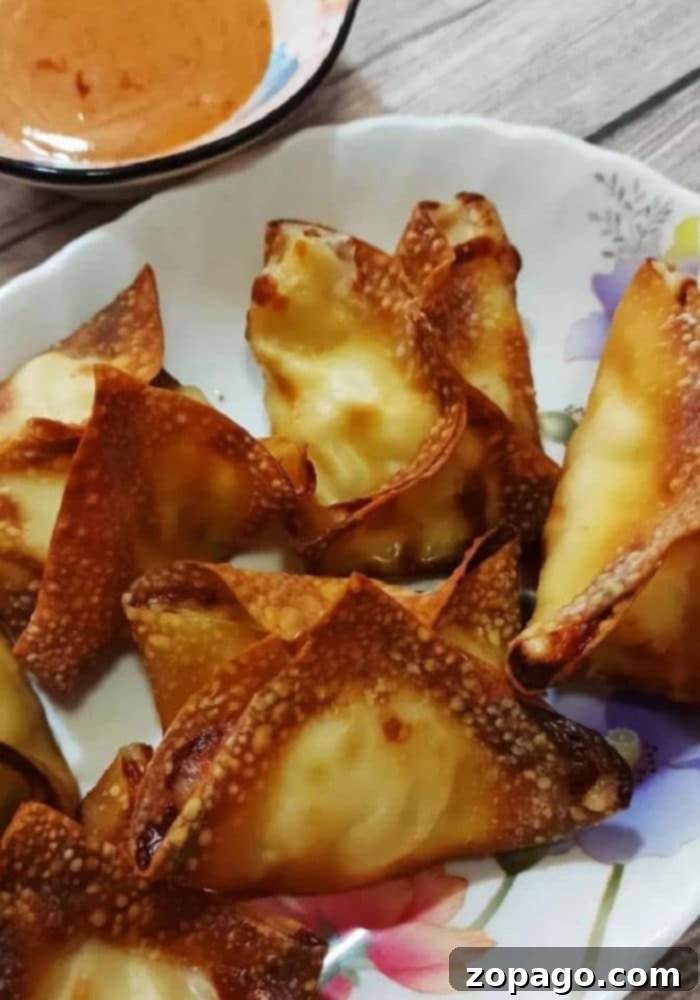 Crispy Air Fryer Ninja Foodi Crab Rangoon 6 Plated Air Fryer Crab Rangoon with a side of homemade dipping sauce, ready to be enjoyed as a crispy appetizer.