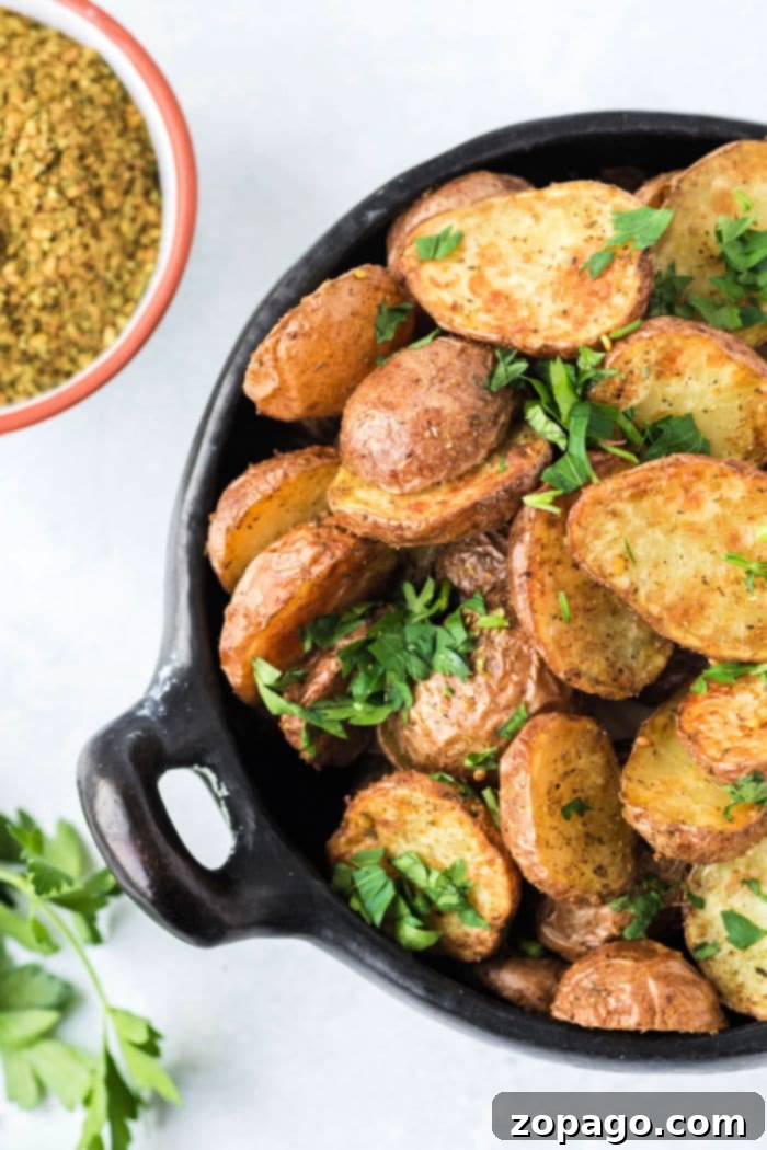 Close-up of small potatoes cooking in an air fryer basket, showing their developing crispy texture.