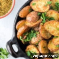 A bowl of seasoned air fryer fried potatoes garnished with fresh parsley, accompanied by a nearby bowl of spice mix.