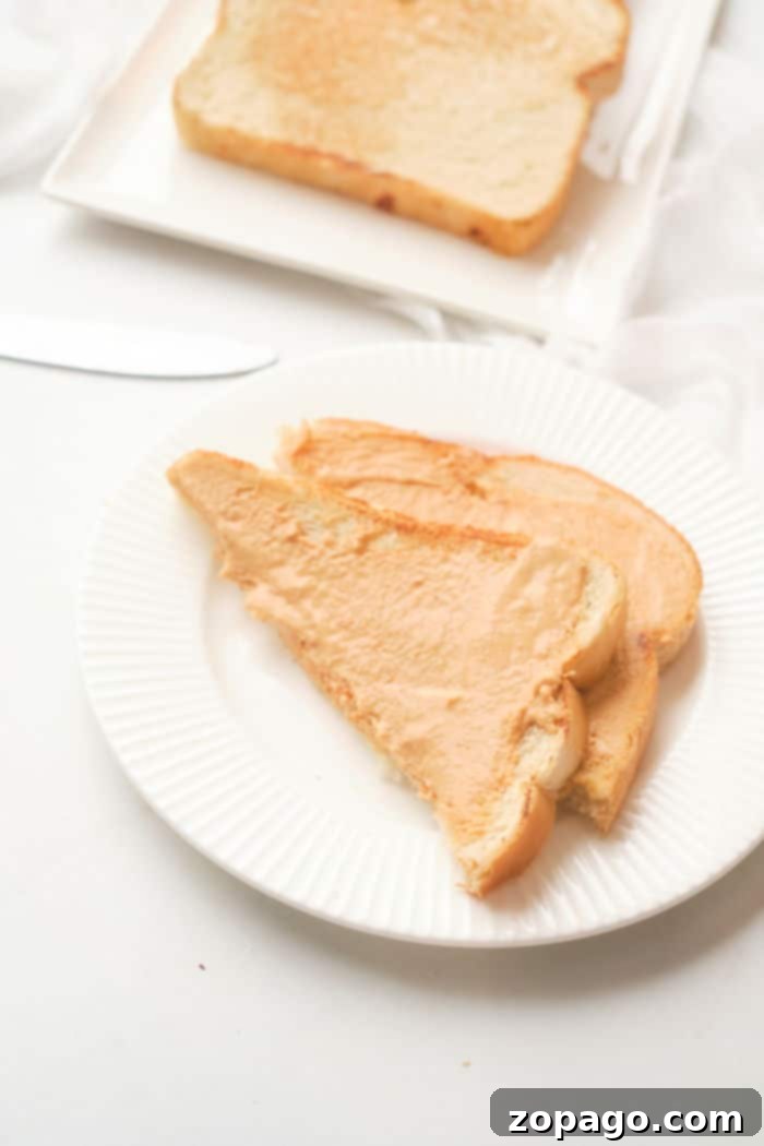 Perfectly Crispy Oven Toast 5 Several slices of golden brown toast with various toppings including peanut butter and fruit, neatly arranged on a white plate next to a knife, demonstrating easy breakfast preparation by making toast in the oven.