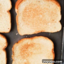 Perfectly Crispy Oven Toast 7 Four slices of golden-brown toast, perfectly crisped by making toast in the oven, rest on a baking tray.