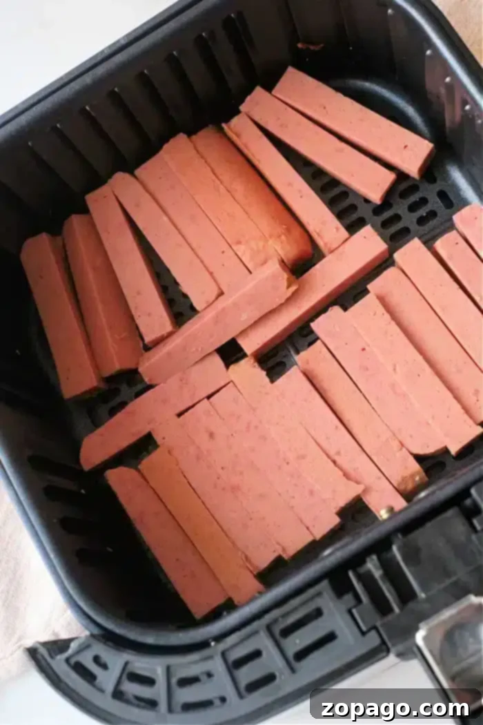 Crispy Air Fryer Spam Fries 6 Sliced pieces of spam are arranged in the basket of an air fryer, ready for cooking
