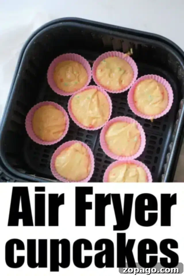 Easy Air Fryer Cupcakes 5 An air fryer basket filled with eight vibrant silicone cupcake molds, each perfectly filled with raw cupcake batter, with the text "Delicious Air Fryer Cupcakes" overlayed.