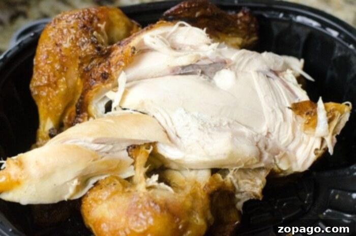 Ultimate Publix Buffalo Chicken Dip 3 Close-up of a cooked rotisserie chicken in a black plastic container, its golden brown skin enticingly crisp, ready to be shredded for a delicious dip or soup.