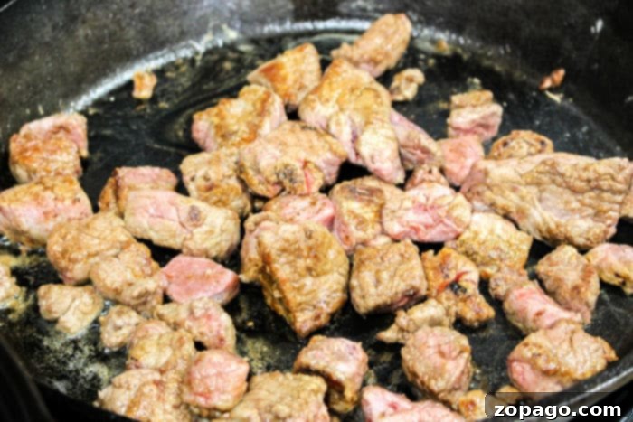 Slow Cooker Beef Stew: The Onion Soup Mix Secret 5 Close-up of beef stew meat browning in a cast iron skillet before being added to the slow cooker.