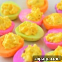 Experience the vibrant hues of Colored Deviled Eggs, featuring bright pink, orange, green, and purple yolks filled with a sunny yellow egg mixture.