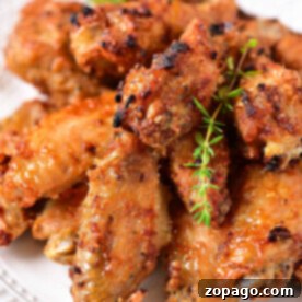 A plate of crispy, golden-brown chicken wings, perfectly suited for reheating in an air fryer, garnished with fresh herbs, signifying delicious leftovers.