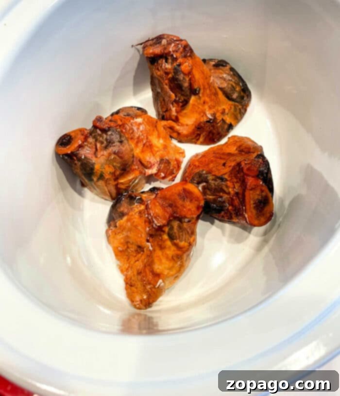 Making Mouthwatering Ham Hocks 2 Four pieces of ham hocks gently simmering in a slow cooker, promising tender meat and rich flavor.